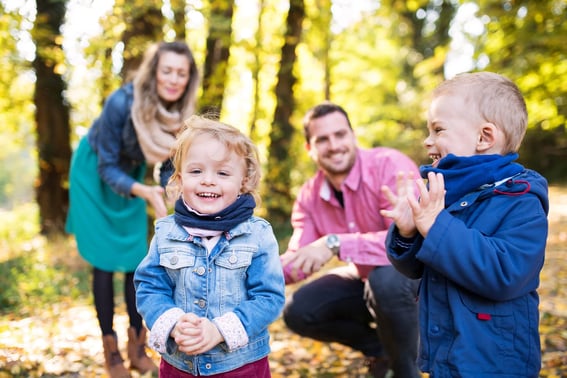 Young family with two small toddlers on a walk in the woods