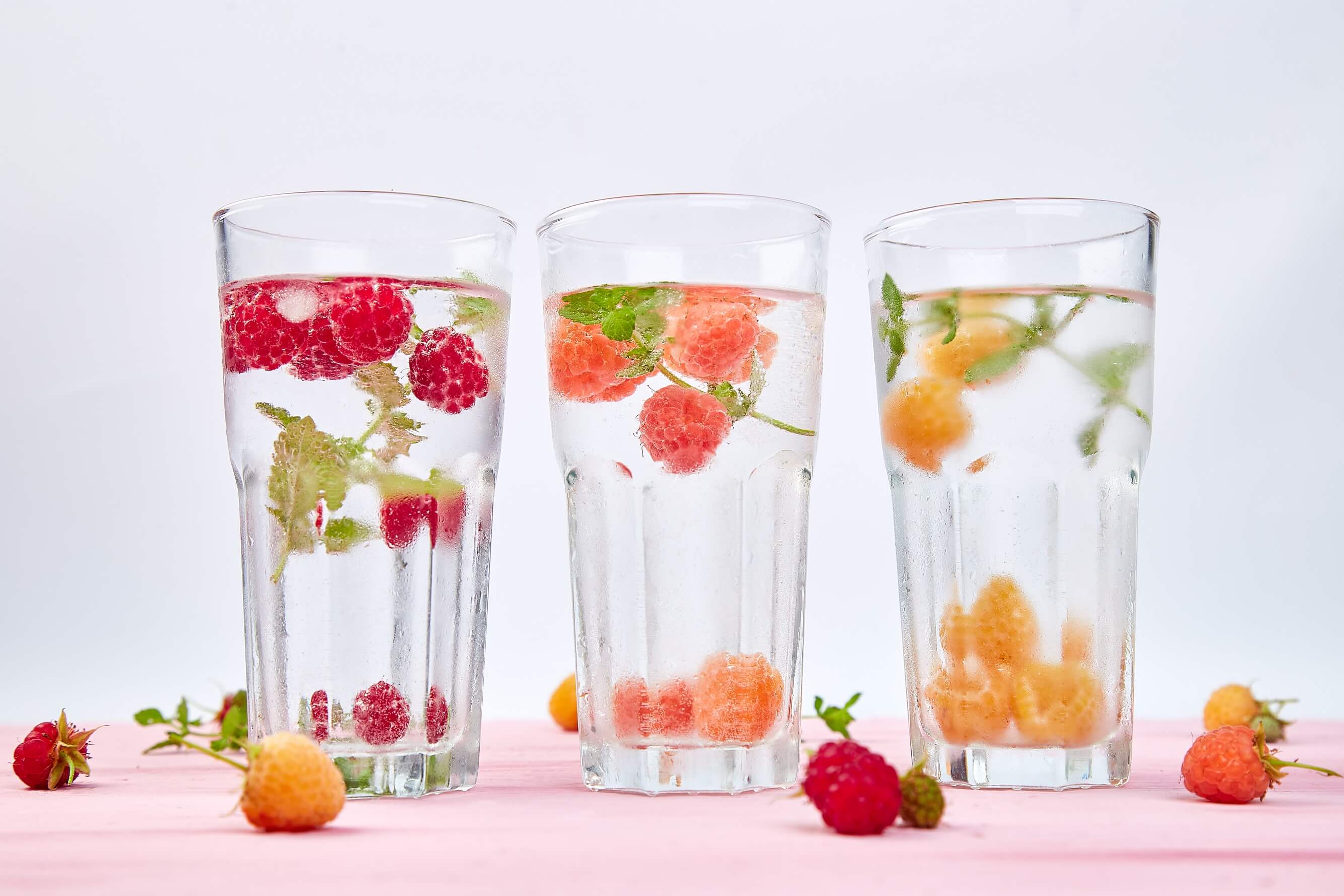three glasses of water with fresh fruit added