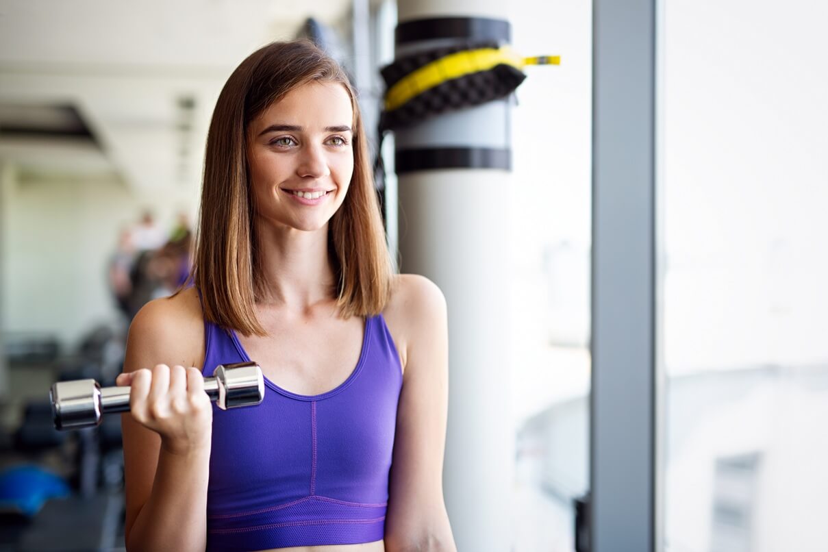 woman in the gym lifting weights and smiling
