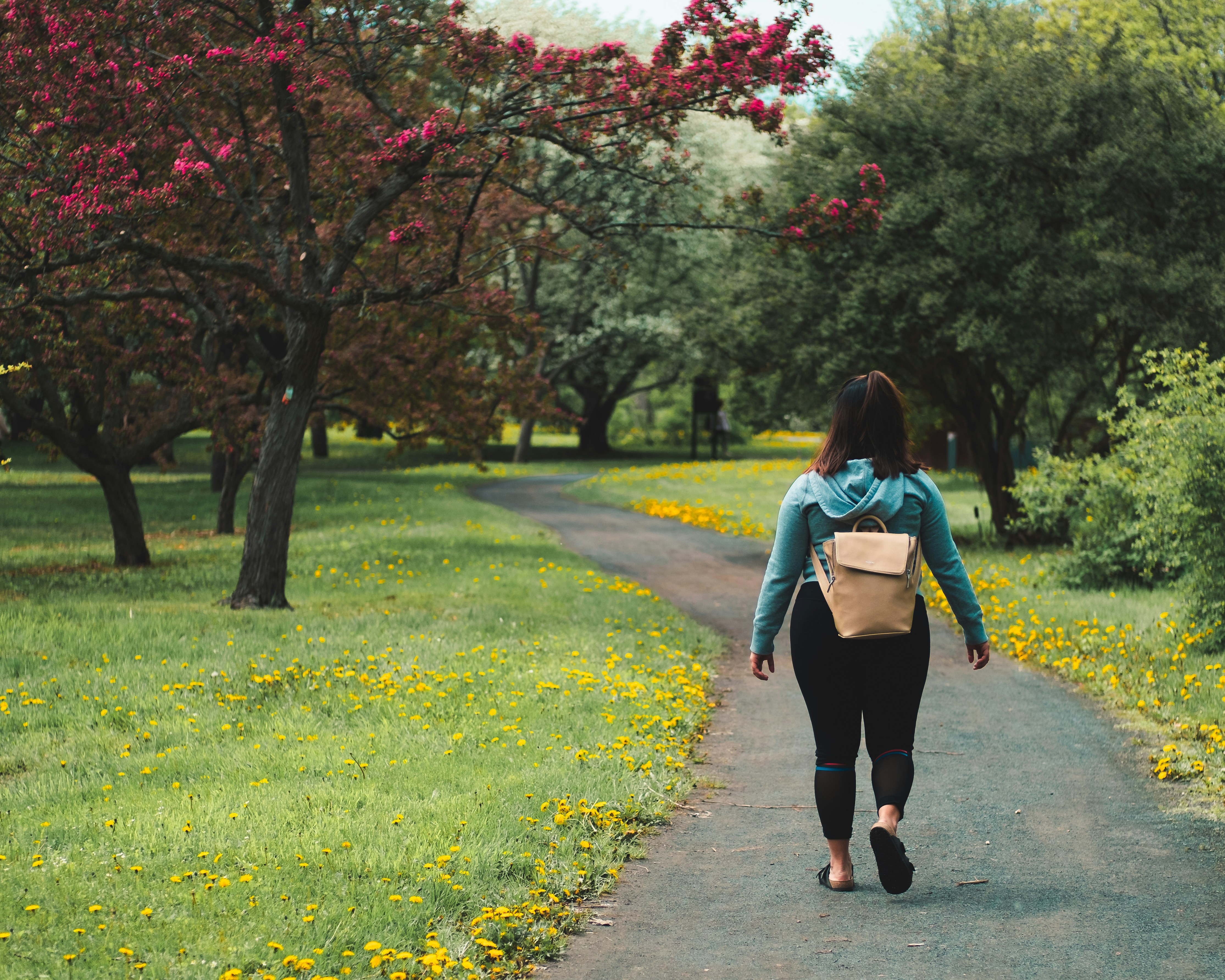 woman walking through a park with greenery