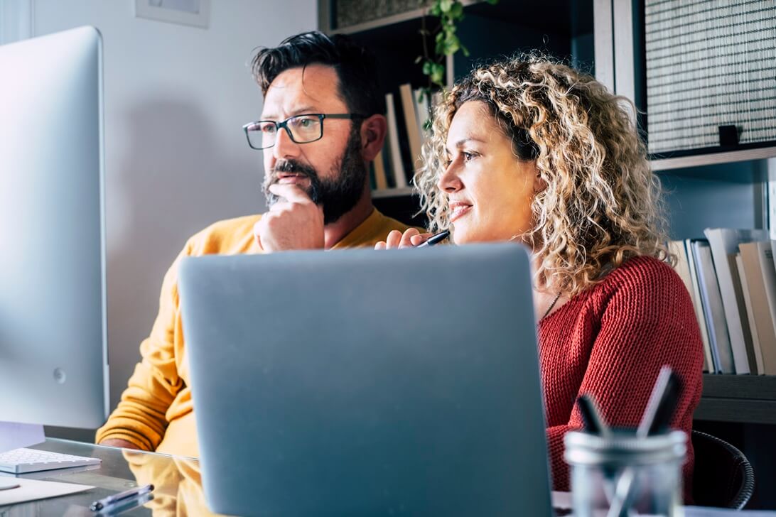 man and woman at home looking at computer screen