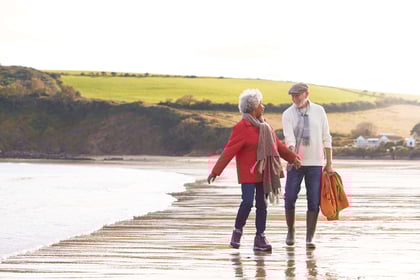 happy senior couple holding hands and walking along the beach