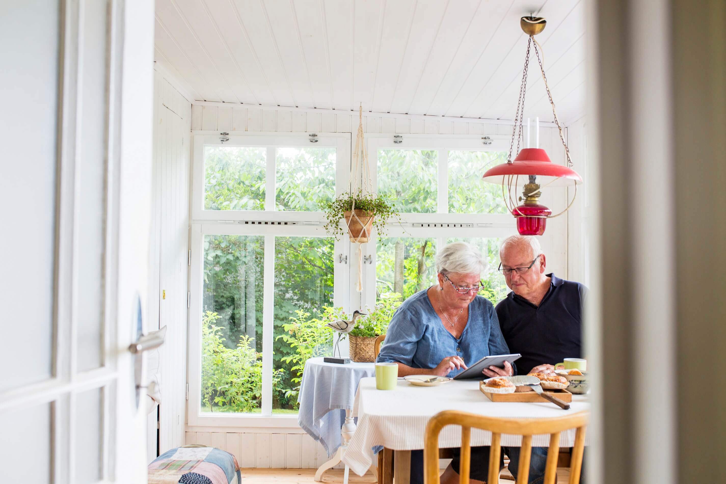 Senior couple sat at the table looking at a tablet