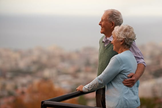 An older couple standing together looking out on a view
