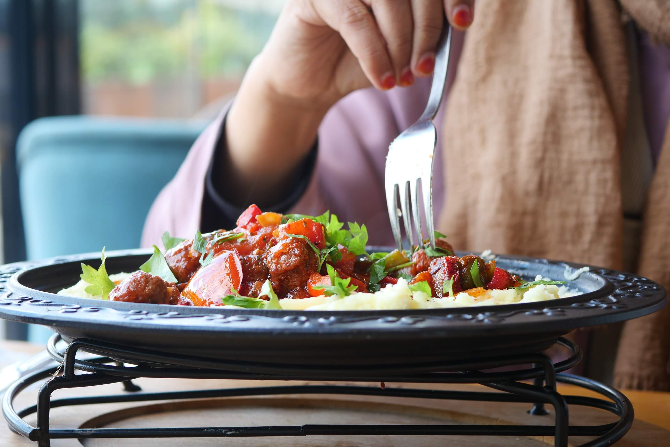 A person eating a pasta meal sat at a table