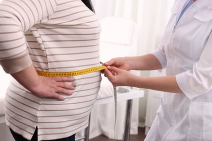 Nutritionist measuring overweight woman's waist with tape