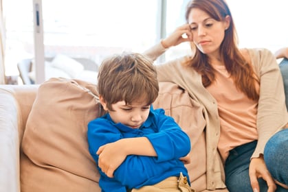 The stressed child and his mother are sitting on the sofa