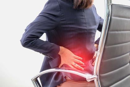 Woman sitting on office chair and feeling back ache