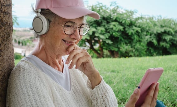 Elderly woman in park with headphones on