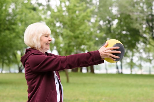 elderly-woman-exercising-with-medicine-ball-in-par-private-medical-insurance